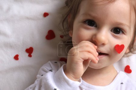 Photo for A baby smiling with of red hearts surrounding him on white. - Royalty Free Image