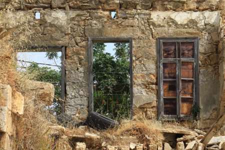 Téléchargez les photos : Une façade de maison en ruine avec une porte fermée et des cadres. - en image libre de droit