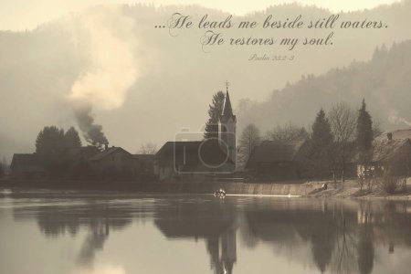Escena fría de la mañana en una orilla del lago con humo que sale de una chimenea en una casa de pueblo con el Salmo 23. 