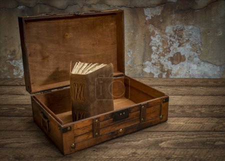 Foto de Caja decorativa retro o caja de almacenamiento en mesa rústica de madera con un viejo diario o libro en el interior - Imagen libre de derechos