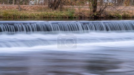 Photo for Water cascading over a diversion dam on the Poudre River with fall scenery, nature and industry concept - Royalty Free Image