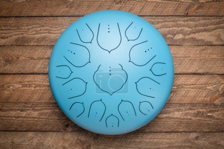 Photo for Blue steel tongue drum,top view against rustic wood - Royalty Free Image
