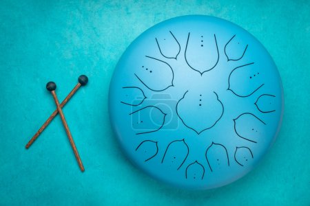 Photo for Blue steel tongue drum with mallets, top view against textured paper background - Royalty Free Image