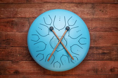 Photo for Blue steel tongue drum with mallets, top view against rustic barn wood - Royalty Free Image