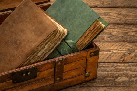 Foto de Libros antiguos o revistas en una caja decorativa retro sobre mesa rústica de madera - Imagen libre de derechos