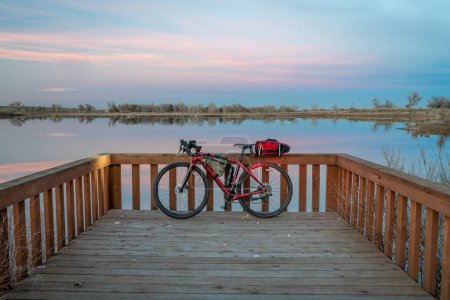 Téléchargez les photos : Vélo de randonnée en gravier avec lumières allumées au bord d'un lac au crépuscule, sentier South Platte River dans le nord du Colorado près de Brighton - en image libre de droit