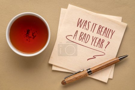 Foto de ¿Fue realmente un mal año? Pregunta manuscrita sobre una servilleta con una taza de té. Resumen y evaluación del año transcurrido. - Imagen libre de derechos