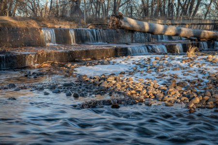 Photo for Water cascading over a diversion dam on the Poudre River with fall or winter scenery, nature and industry concept - Royalty Free Image
