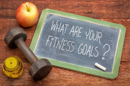 Photo for What are your fitness goals? White chalk text on a slate blackboard with a dumbbell, apple and tape measure. Goal setting and planning exercise activities. - Royalty Free Image