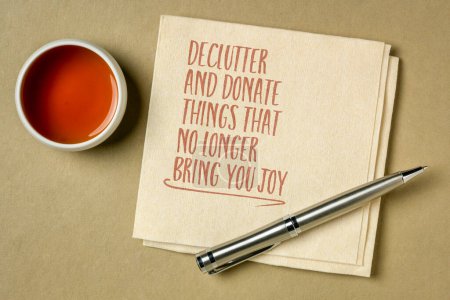 declutter and donate thing that no longer bring you joy - inspirational note on a napkin with a cup of tea, simplicity, minimalism and personal development concept