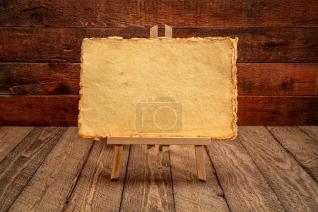 Téléchargez les photos : Petit panneau de chevalet avec papier jaune fait main sur fond de bois rustique et altéré - en image libre de droit
