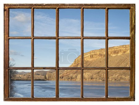 Photo for Sunset light over a frozen lake and sandstone cliff at Colorado foothills, vintage sash window view - Royalty Free Image