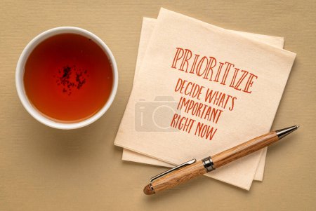 Foto de Priorizar, decidir lo que es importante en este momento - consejos inspiradores o recordatorio en una servilleta con una taza de té, productividad y concepto de desarrollo personal - Imagen libre de derechos