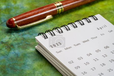 Téléchargez les photos : Avril 2023 - petit calendrier de bureau en spirale avec un stylo élégant contre le papier marbré, le temps et le concept d'entreprise - en image libre de droit