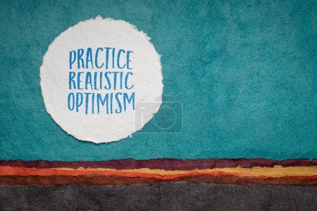Foto de Práctica optimismo realista - consejo inspirador o recordatorio, escritura contra el paisaje abstracto de papel, concepto de positividad - Imagen libre de derechos