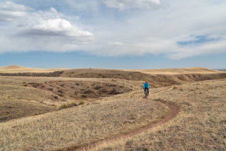 Photo for Senior male cyclist is riding a gravel bike on a single track trail in Colorado foothills in early spring scenery, Soapstone Prairie Natural Area - Royalty Free Image