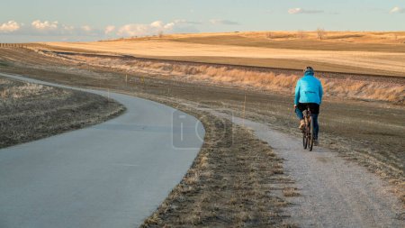 Téléchargez les photos : Coucher de soleil sur une piste cyclable avec un cycliste senior sur un vélo de gravier dans les contreforts du Colorado entre Fort Collins et Loveland, début du printemps paysage - en image libre de droit