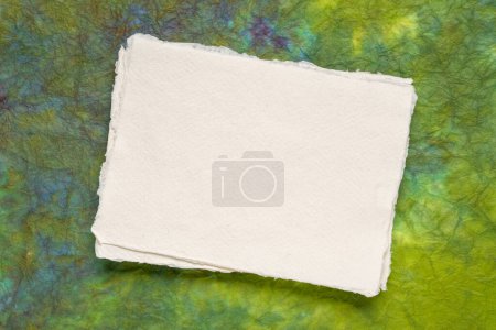 Foto de Pequeña hoja de papel de trapo blanco Khadi en blanco del sur de la India contra papel de mármol verde - Imagen libre de derechos