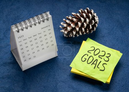 Photo for 2023 goals - handwriting in black ink on a reminder note with a January desktop calendar and frosty pine cone, New Year goals and resolutions concept - Royalty Free Image