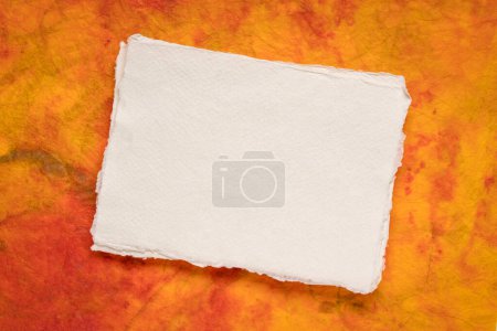 Téléchargez les photos : Petite feuille de papier blanc blanc Khadi chiffon contre papier marbré coloré - en image libre de droit