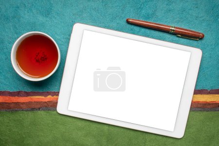 Photo for Mockup of digital tablet with a blank isolated screen (clipping path included), flat lay with a cup of tea against abstract paper landscape - Royalty Free Image