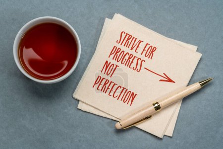 Téléchargez les photos : Viser le progrès, pas la perfection - écriture manuscrite sur une serviette avec un thé, succès et concept de développement personnel - en image libre de droit