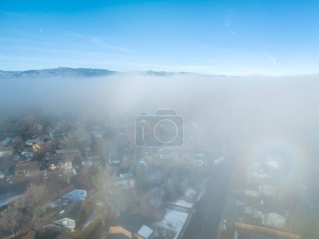 Téléchargez les photos : Foggy winter morning over Rocky Mountains and Fort Collins, Colorado, aerial view with a faint rainbow halo on a fog layer - en image libre de droit