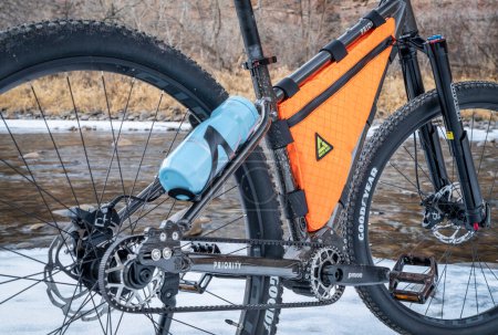 Foto de Fort Collins, CO, USA - January 16, 2023: Carbon fiber-reinforced drive belt and  an enclosed Pinion gearbox on the 600x Priority adventure mountain bike.with a frame bag and bottle. - Imagen libre de derechos