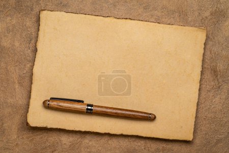 Téléchargez les photos : Sheets of blank handmade paper with rough edges and a stylish pen against textured bark paper - en image libre de droit