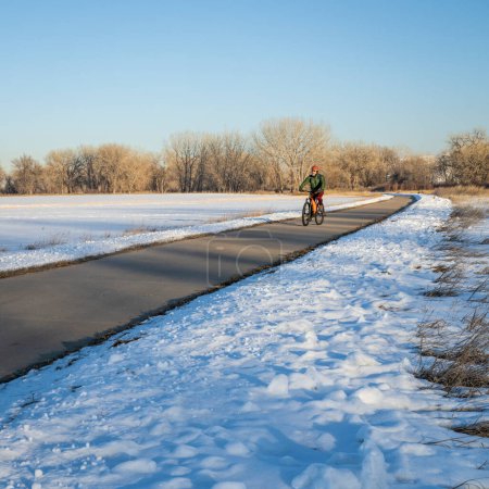 Téléchargez les photos : Cycliste senior sur une piste cyclable dans les paysages d'hiver - Poudre River Trail dans le nord du Colorado, concept de vélo, de loisirs et de transport - en image libre de droit