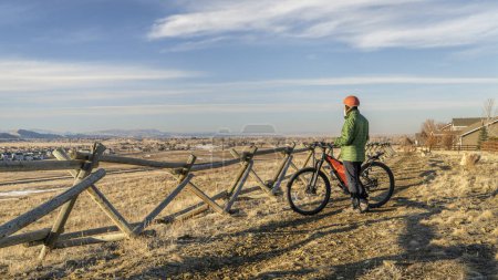 Téléchargez les photos : Senior male cyclist with a mountain bike on a dirt trail overlooking Colorado foothills - en image libre de droit