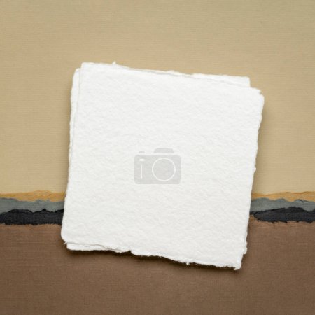 Foto de Pequeña hoja cuadrada de papel blanco Khadi en blanco contra abstracto en tonos tierra - Imagen libre de derechos