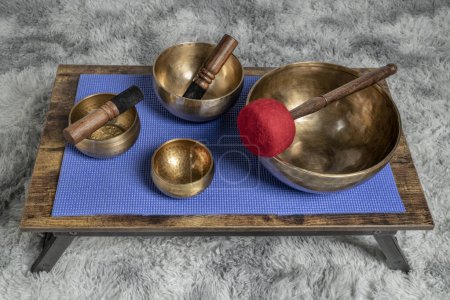 Foto de Gran tazón de canto tibetano con una vela de mazo, rodillo y cera en una mesa baja, curación de sonido y concepto de meditación - Imagen libre de derechos