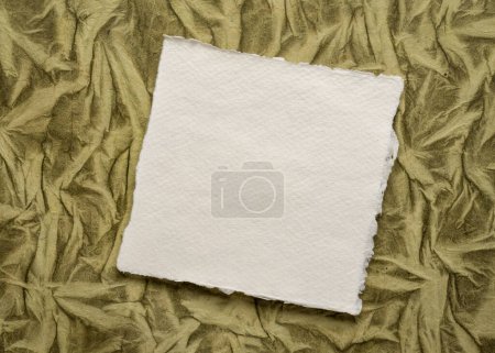 Foto de Pequeña hoja de blanco blanco papel de trapo Khadi contra el fondo de papel de arte - Imagen libre de derechos