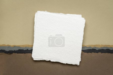 Foto de Pequeña hoja cuadrada de papel blanco en blanco contra el paisaje abstracto en tonos de tierra - Imagen libre de derechos
