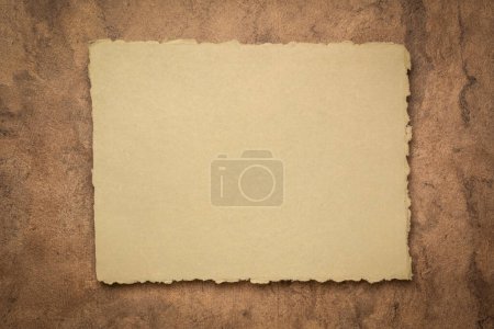 Foto de Abstracto en tono tierra, una hoja de papel de trapo indio en blanco contra papel de corteza texturizado, espacio de copia - Imagen libre de derechos