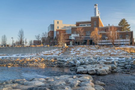 Téléchargez les photos : Poudre River dans un parc d'eau vive au centre-ville de Fort Collins Colorado avec Powerhouse Energy Campus de l'Université d'État du Colorado en arrière-plan, paysage de coucher de soleil d'hiver - en image libre de droit