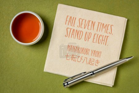 Téléchargez les photos : Tomber sept fois, se lever huit fois. Proverbe japonais sur une serviette avec une tasse de thé. Concept de détermination et de persistance. - en image libre de droit