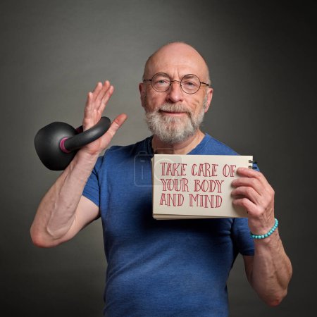 Photo for Take care of your body and mind - motivational note held by a senior man exercising with iron kettlebell, active senior, fitness and self care concept - Royalty Free Image