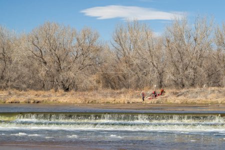 Téléchargez les photos : Evans, CO, États-Unis - 1er avril 2023 : Les kayakistes transportent des kayaks sur un barrage de dérivation lors d'un voyage de pagaie printanier sur la rivière South Platte au Colorado. - en image libre de droit