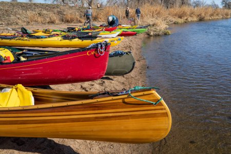 Téléchargez les photos : Evans, CO, États-Unis - 1er avril 2023 : Canoës et kayaks alignés sur une plage avant le voyage de pagaie printanier sur la rivière South Platte. - en image libre de droit