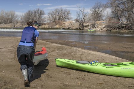 Téléchargez les photos : Evans, CO, États-Unis - 1er avril 2023 : Les pagayeurs transportent des kayaks sur un barrage de dérivation lors d'un voyage de pagaie printanier sur la rivière South Platte au Colorado. - en image libre de droit