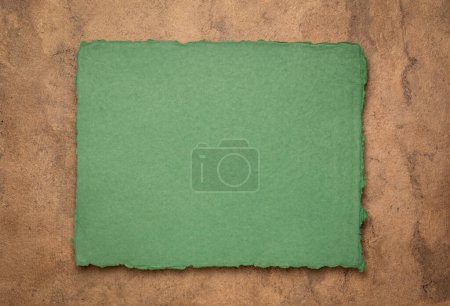 Téléchargez les photos : Vert et brun abstrait - une feuille de papier chiffon indien vierge fait à la main contre du papier d'écorce texturé, espace de copie - en image libre de droit