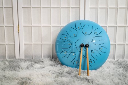 Téléchargez les photos : Tambour de langue en acier bleu avec maillets sur un tapis moelleux - en image libre de droit