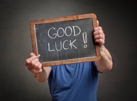 Photo for Good luck sign - white chalk handwriting on a vintage slate blackboard held by a person - Royalty Free Image