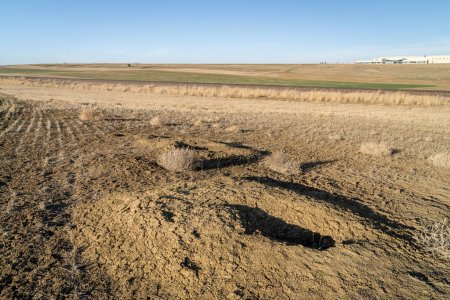 Foto de Paisaje de primavera temprana de las estribaciones del norte de Colorado con guaridas de perro de pradera, tierras de cultivo, ferrocarril y construcción industrial - Imagen libre de derechos