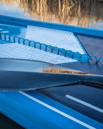 Téléchargez les photos : Pagaie humide et une laisse de sécurité enroulée sur un pont de stand up paddleboard - en image libre de droit