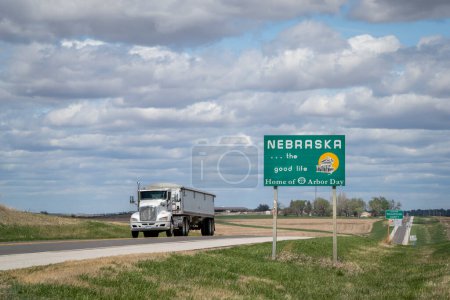 Téléchargez les photos : Nebraska, la belle vie, maison du jour de l'Arbor - panneau de bienvenue au bord de la route à la frontière de l'État avec le Kansas, paysage printanier - en image libre de droit