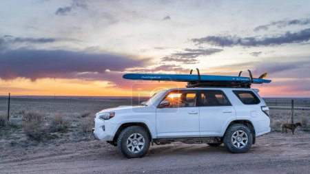 Photo for Julesburg, CO, USA - April 20, 2023: Toyota 4Runner SUV with a performance stand up paddleboard (Starboard Waterline) against sunset over prarie in eastern Colorado. - Royalty Free Image