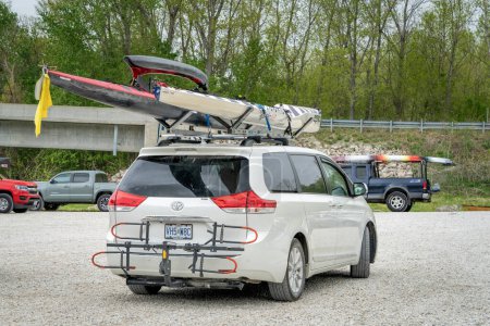 Photo for Lamine, MO, USA - April 22, 2023: Toyota Sienna minivan with racing boats on roof racks, Epic surfski and outrigger canoe after a race on Lamine River. - Royalty Free Image